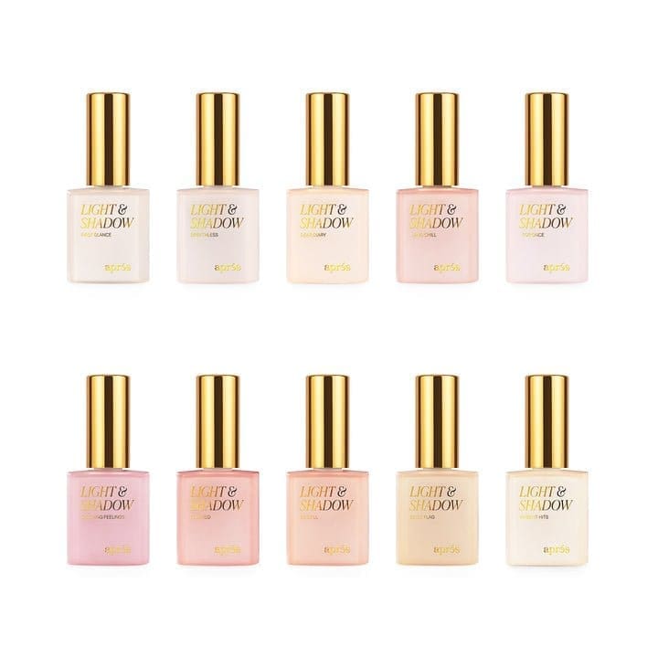 An arrangement of ten bottles labeled "Apres Light & Shadow Sheer Gel Collection 10ml" with golden caps, in two rows of five each, showcasing sheer gel shades ranging from light pinks to nudes.
